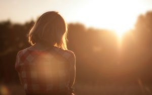 Nainen rukoilemassa Jumalaa auringonlaskun aikaan